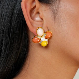 Boucles d'oreilles fleurs en résine avec cristaux et base dorée sur un mannequin