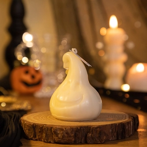 Ghost-shaped scented candle on a rustic wooden base with Halloween pumpkin decor