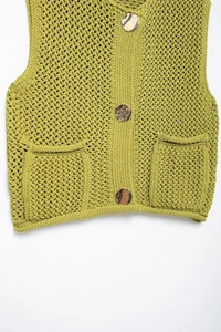 Detail of green knit sweater vest with coarse texture and decorative gold-tone metal buttons