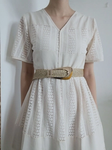 Detail of hand-woven beige belt with a gold irregular metal buckle on a lace dress