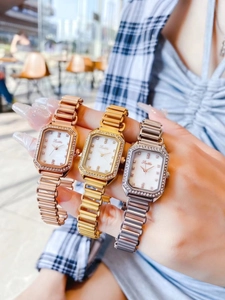 Close-up of three luxury square quartz watches with diamond bezels in rose gold, gold, and silver