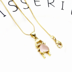 Macro shot of gold-plated necklace with a pink teardrop gem and lobster clasp detail