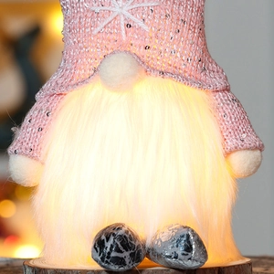 Close-up of glowing Christmas faceless gnome with warm interior light and pink sequins