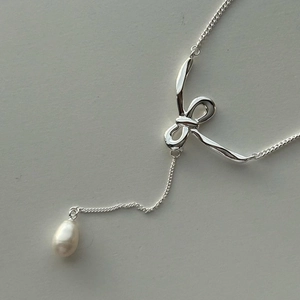 Silver bow necklace with natural freshwater pearl pendant on a minimalist background
