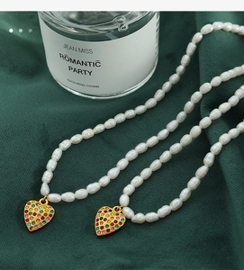 Detail of freshwater pearl necklace with gold heart pendant and colorful rhinestones
