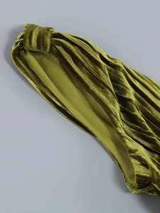 Vue macro d'un bandeau en velours vert olive avec texture plissée et finition brillante