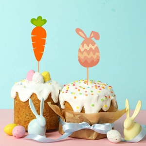 Easter cake toppers with carrot and bunny egg designs on a decorated cream cake