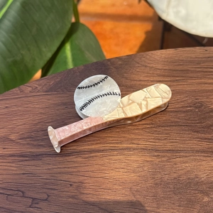 Détail de la pince à cheveux en acétate en forme de batte et balle de baseball sur bois