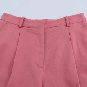 Détail du short rose à taille haute avec passants et texture de tissu plissé