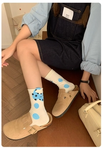 Dettaglio di calze con gatto e sabot in pelle scamosciata beige per un look casual