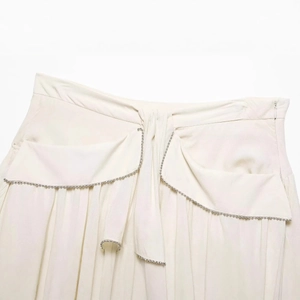 Chic off-white layered mini skirt with asymmetric pleats and delicate pearl trim detailing