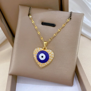 Detail of gold heart pendant with blue evil eye and sparkling zircon stones in a jewelry box