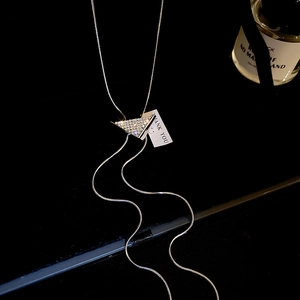 Macro shot of a sparkling silver triangular pendant with a thank you tag on snake chain
