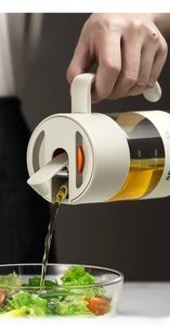 Détail d'une burette en verre à ouverture automatique versant sur une salade