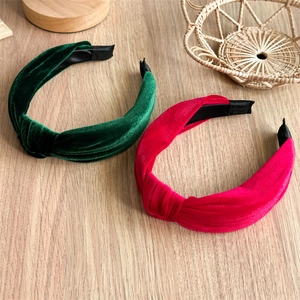 Detail of twisted velvet headbands in green and red with soft plush texture on wood