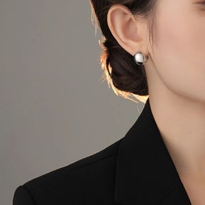 Close-up of a minimalist silver ball earring on model showing polished mirror finish