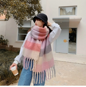 Close-up of rainbow plaid scarf with long fringes and knit hat in winter outdoor setting