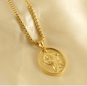 Dettaglio macro della collana con ciondolo a rilievo ovale oro su tessuto