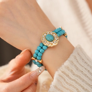Gros plan sur bracelet double rang de perles bleues avec fleur dorée et turquoise