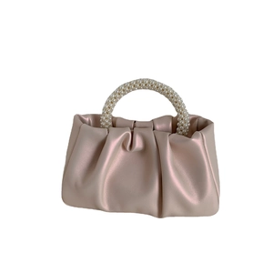 Champagne gold gathered cloud handbag with a decorative pearl bead handle on white background