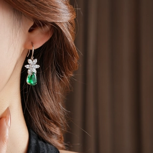 Gros plan de boucles d'oreilles fleur en argent avec pendentifs zircon goutte verte