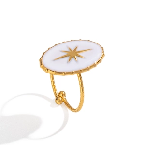 Gros plan d'une bague dorée avec émail blanc et motif d'étoile sur anneau torsadé