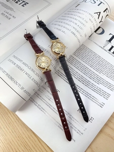 Close-up of vintage quartz watches with leather straps and Roman numeral gold cases