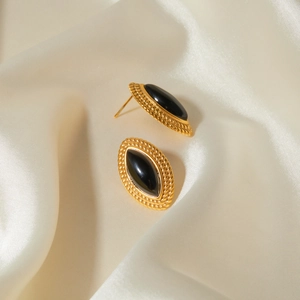 Macro detail of vintage 18k gold earrings with black marquise onyx and braided texture