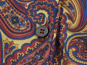 Gros plan sur le tissu à motif paisley rouge et bleu avec un bouton marron détaillé
