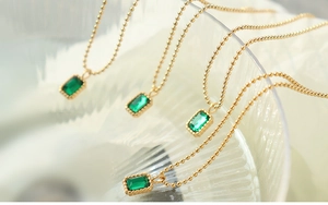 Detailed macro of 18K gold emerald green zircon necklace with vintage beaded bezel edge