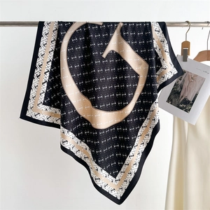 Close-up of elegant black and beige scarf with chain print and classic pattern