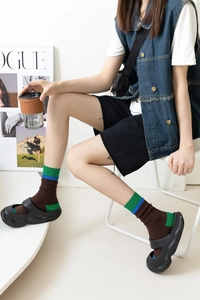 Close-up of color-block crew socks paired with black platform Mary Jane sandals