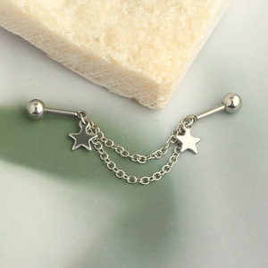 Close-up of silver industrial barbell with star charms and delicate double hanging chains