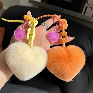 Plush heart keychains in off-white and orange with plastic chains and purple heart charms