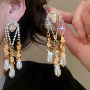 Detailed macro view of gold-plated tassel earrings with sparkling crystals and water drop pearls