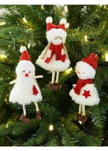 Detail of plush Santa, girl and snowman ornaments hanging on a lighted Christmas tree