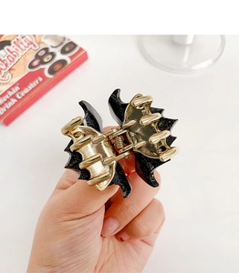 Detail of black glitter bat hair claw clip with golden metal spring and acrylic finish