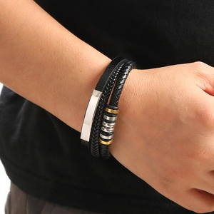 Multilayer black leather woven bracelet with silver metal plate and gold beads on a wrist