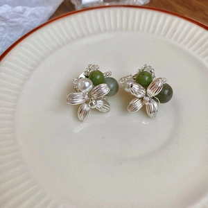 Detailed macro view of floral silver needle earrings with green agate and pearls