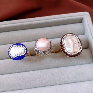 Macro shot of 18k gold-plated pearl rings with colorful rhinestones in a gray velvet box