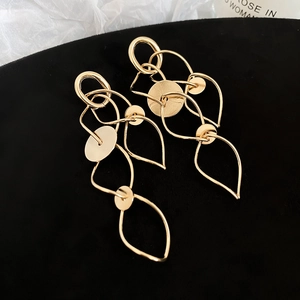 Macro shot of gold geometric tassel earrings with leaf cutouts on black velvet