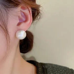Minimalist large white hemispherical pearl stud earrings with a brushed metal texture