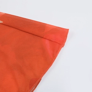 Détail du tissu en maille orange montrant la texture fine et la qualité de la couture