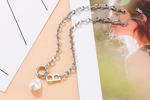Detailed view of silver B-letter pendant necklace with a white baroque pearl accent