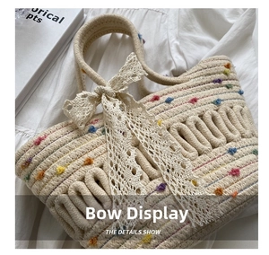 Close-up of woven straw bucket bag with colorful pom-poms and white lace bow detail