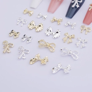 Detailed view of gold and silver alloy bow nail charms on a soft purple background