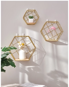 Three-piece gold hexagonal wall shelves with wood base in a bright minimalist setting