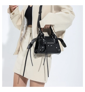 Detail view of black patent leather mini crossbody bag with silver studs and tassels