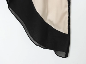 Detail von elegantem schwarzem Netzgewebe auf champagnerfarbenem Satin-Midi-Kleid