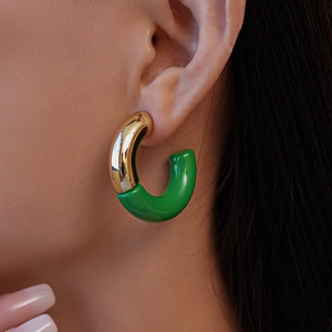 Close-up of model wearing C-shaped acrylic earrings in gold and green color blocking